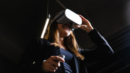 A brown-haired white woman smiling and using a VR headset