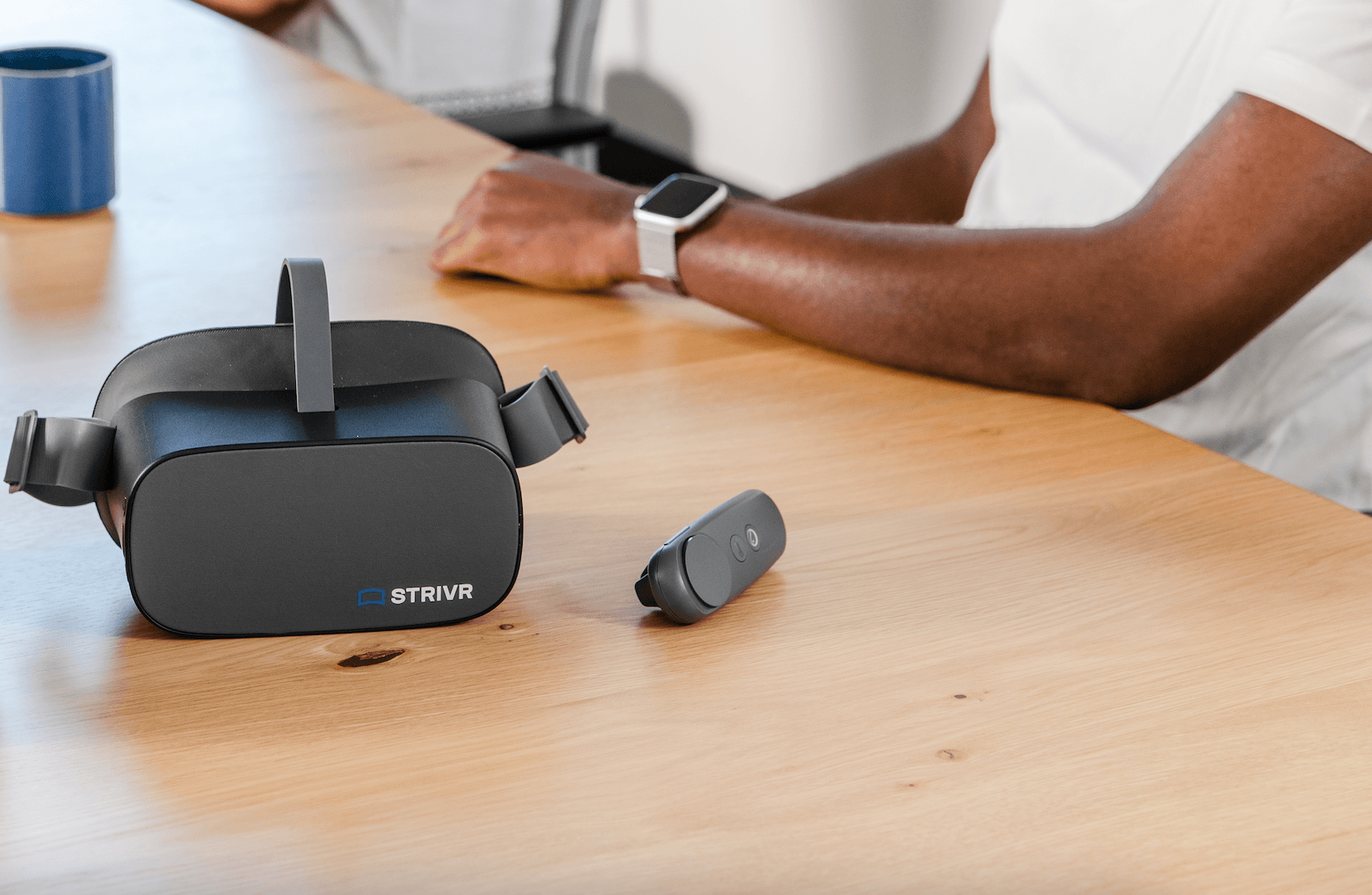 Strivr VR headset and handheld controller sitting on table in front of a black man